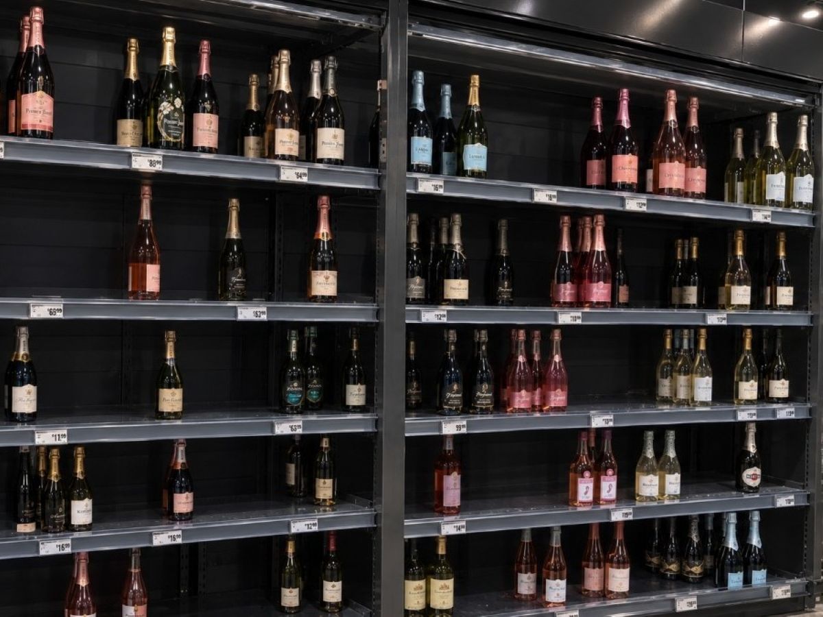 Disorganized wine shelf before pusher installation with recessed bottles and invisible out-of-stocks