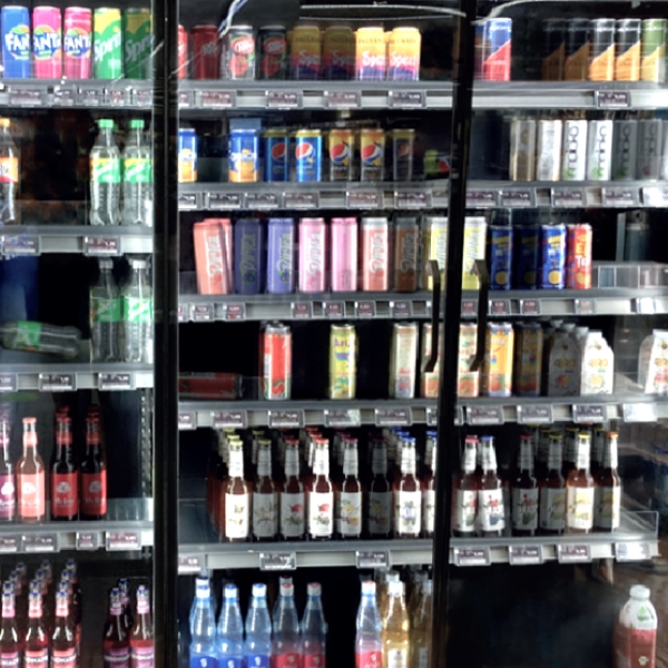 Before: messy beverage gondola with mixed-format cans and bottles tipped, uneven, and pushed to the back of the shelf